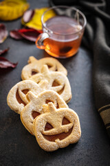 Linzer cookies in the shape of a Halloween pumpkin on black table.