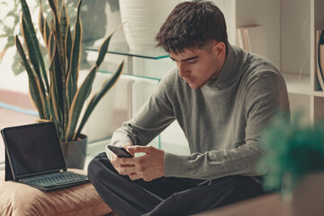 young man or teenager at home with mobile phone