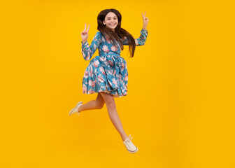 Fototapeta na wymiar Teenager girl jumping. Full length of her she playful preteen teenager girl having fun and jumping isolated on yellow background.