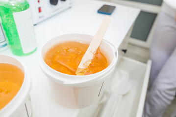 Plastic bucket with sugaring paste on white background