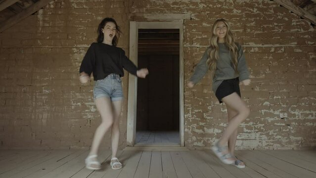 Teenage girls performing dance routine in empty attic / Grafton, Utah, United States