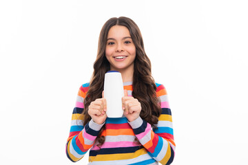 Teenager child girl showing bottle shampoo conditioners or shower gel isolated on white background. Hair cosmetic product. Mock up bottle. Happy girl face, positive and smiling emotions.