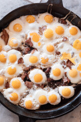 Delicious breakfast outside. Huge scrambled eggs with bacon in a frying pan close-up.