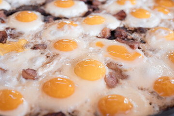 Delicious breakfast outside. Huge scrambled eggs with bacon in a frying pan close-up.