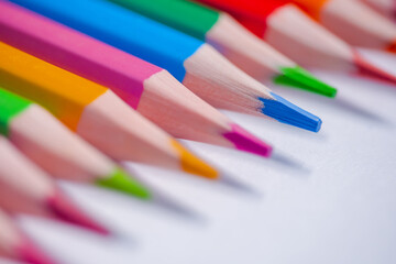 Many different colored pencils in row on white surface - close up, selective focus, macro....