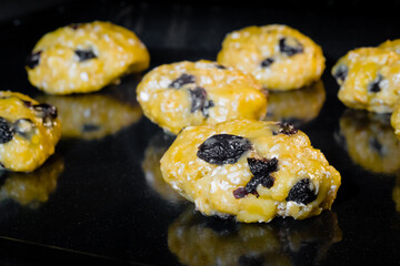Many uncooked homemade yellow oatmeal raisin cookies on metal sheet in oven - close up. Dessert, baking, gastronomy, food concept