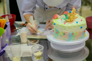 Chef, confectioner hands decorating child birthday dessert cake - close up. Professional cooking, bakery, cookery, gastronomy, pastry and food concept