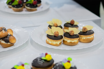 Assortment of delicious fresh shortcrust tart cakes with cream and chocolate on white plate for sale at restaurant, cafe, bakery. Dessert, culinary, sweet food and confectionery concept