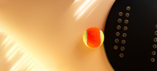 Black professional beach tennis racket and ball on beige background. Horizontal sport theme poster, greeting cards, headers, website and app