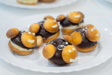 Assortment of delicious fresh shortcrust tart cakes with chocolate and sweet mushrooms on white plate for sale at restaurant, cafe - close up. Dessert, culinary and confectionery concept
