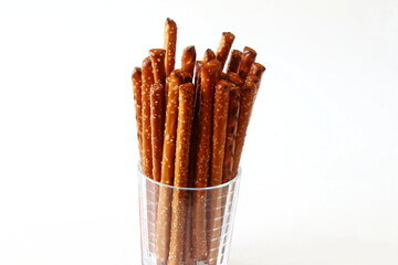 Salted Baked brown Pretzel Sticks in glass on white background
