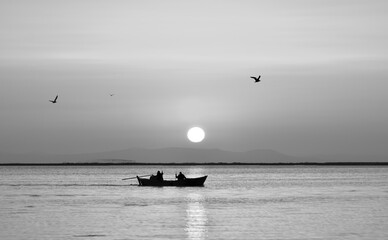 Fishing boat on a sea, seagulls flying. Black and white photo 