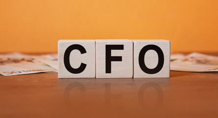 CFO - an inscription on wooden cubes on an orange background along with banknotes. Finance and wear concept.