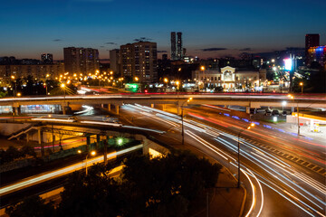 City highway traffic - street with fast moving cars and lights trails - long exposure. Warm illumination at night. Rush hour, urban, transportation and city life concept
