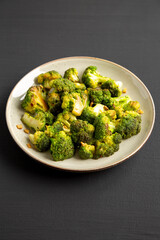 Homemade Pan-Fried Broccoli on a Plate on a black background, side view.