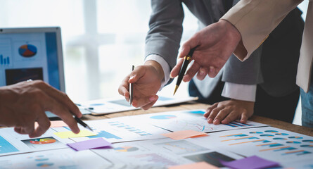 Financial analyst analyzes business finance reports on laptop and graph documents during corporate meeting discussions showing successful teamwork, business meeting ideas, marketing.