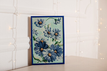Gesticktes Blumenmotiv Kornblumenim Rahmen hinter Glas
