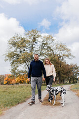 A happy couple walks their dog dalmation