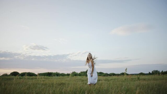 Pretty woman runs across field smiling against twilight sky