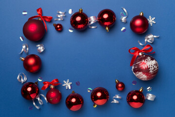 Christmas ball toys and confetti on color background, top view