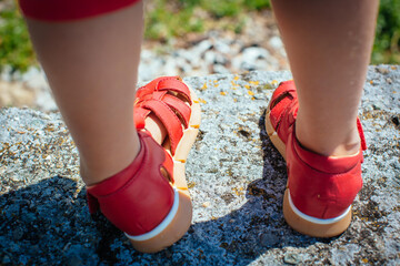 Kinderfüße in roten Sandalen von hinten