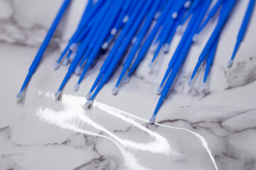 Set of blue microbrushes for eyelashes on a light marble background