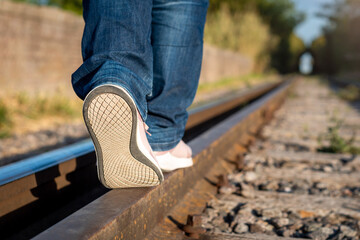Mujer caminando en las vías del tren, haciendo equilibrio. Fotografía con enfoque selectivo en...