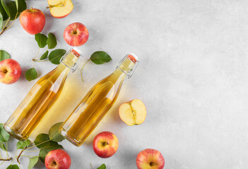 Apple cider vinegar of fermented fruit into a two glass bottles with fresh organic ripe red apples on light background. Vitamin superfood drink, Healthy eating lifestyle concept, top view, copy space