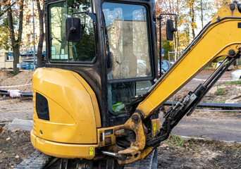 Small bulldozer at work. Orange excavator on the road.  Construction works in the city.