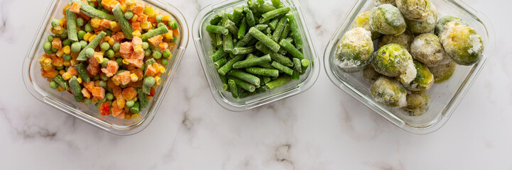 Frozen vegetables in containers banner , frozen cauliflower and asparagus beans, peas and corn, Brussels sprouts and carrots, mix of vegetables, top view, copy space