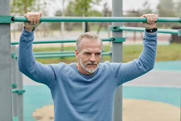 Naklejka premium Portrait of handsome mature man working out outdoors and looking away with motivation in minimal city setting
