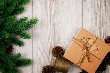 Fir branches and cones. Christmas background with decorations, reindeer and gift boxe on wooden board. Top view.