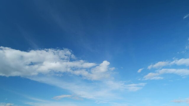 Summer sky. Cirrus and cumulus on different layers clouds on bright blue sky. Wispy cirrus clouds pass over blue sky in nature. Timelapse.