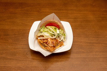 Lamb kebab sandwich with salad, meat, lettuce and onion on a white plate