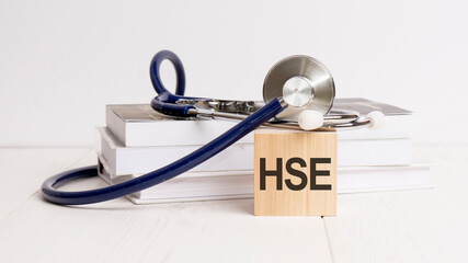 the word HSE is written on wooden cube near a stethoscope on a white background. medical concept