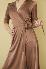 Serie of studio photos of young female model in brown silk satin wrap midi dress.	