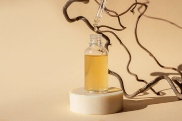 An open cosmetic bottle of serum or oil and a pipette on a beige natural background. Facial skin...