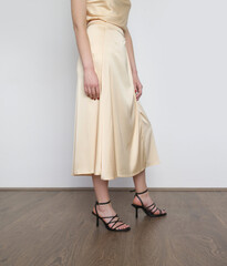 Female model wearing beige camisole silk top and wrapped midi skirt. Stylish and elegant monochrome...
