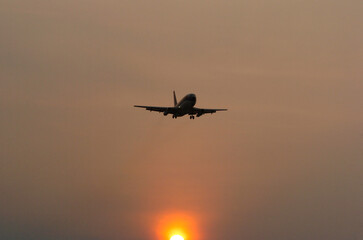 Silhouette image of a passenger plane about to land at the airport, at sunset. Safe felling when the weather is sunny