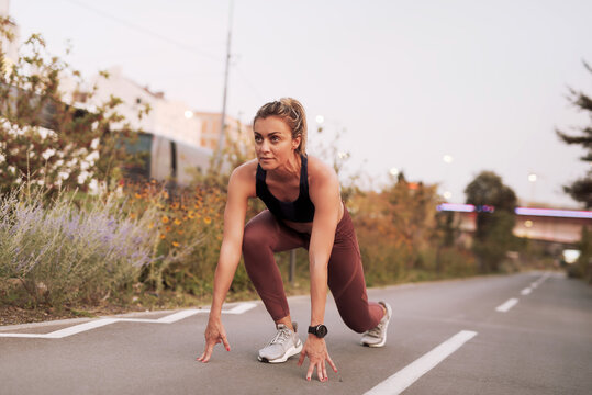 Mature woman in a starting position ready to start running fast, sprinter, exercising and working out