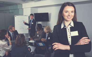 Portrait of confident business woman in meeting room with working group behind