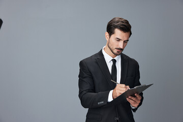 Portrait of a business man in a stylish suit smile with teeth hands up handsome face on gray isolated background with tablet in hand. Business concept young businessman startup copy space.