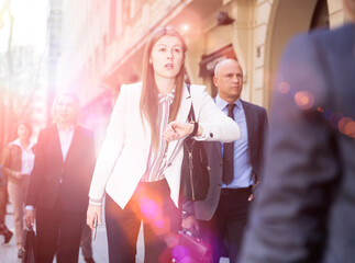 Woman in business suit hurry up and walking fast down the street among people