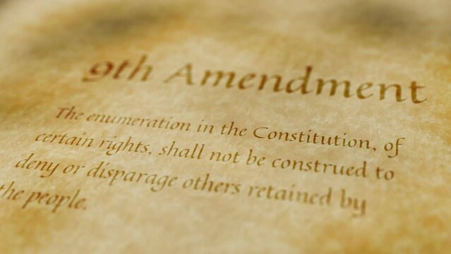 Scrolling text on old paper background of contents of 9th amendment to the United States Constitution that guarantees that people have rights other than those explicitly guaranteed in Bill of Rights
