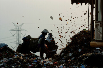 Scavengers, looking for useful items at a garbage dump site, before sunset