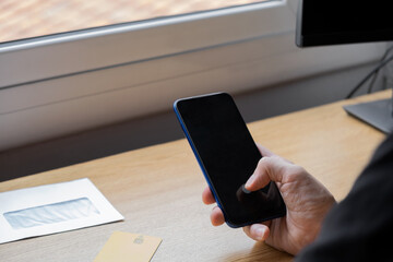 hand holding phone with blank screen, yellow credit card on the table, 
