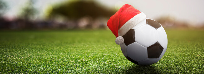 soccer football ball with christmas hat on a field