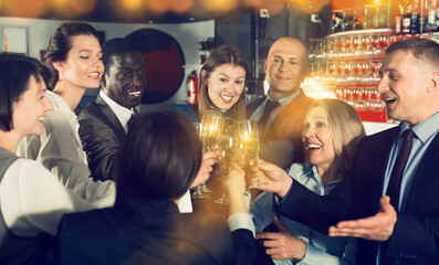 International group of cheerful positive smiling businesspeople toasting with champagne, having fun at office party in nightclub