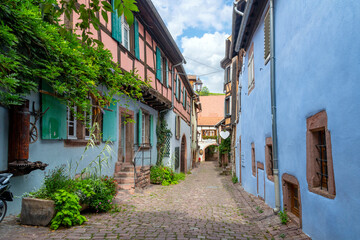 Fototapeta na wymiar A colorful alley of medieval half timber homes in the French village of Ribeauville, France, one of the stops on the wine route in the Alsace region.