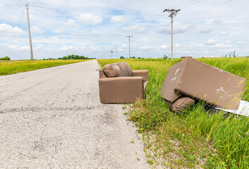 Furniture dumped in ditch of road. Fly dumping, pollution and littering concept